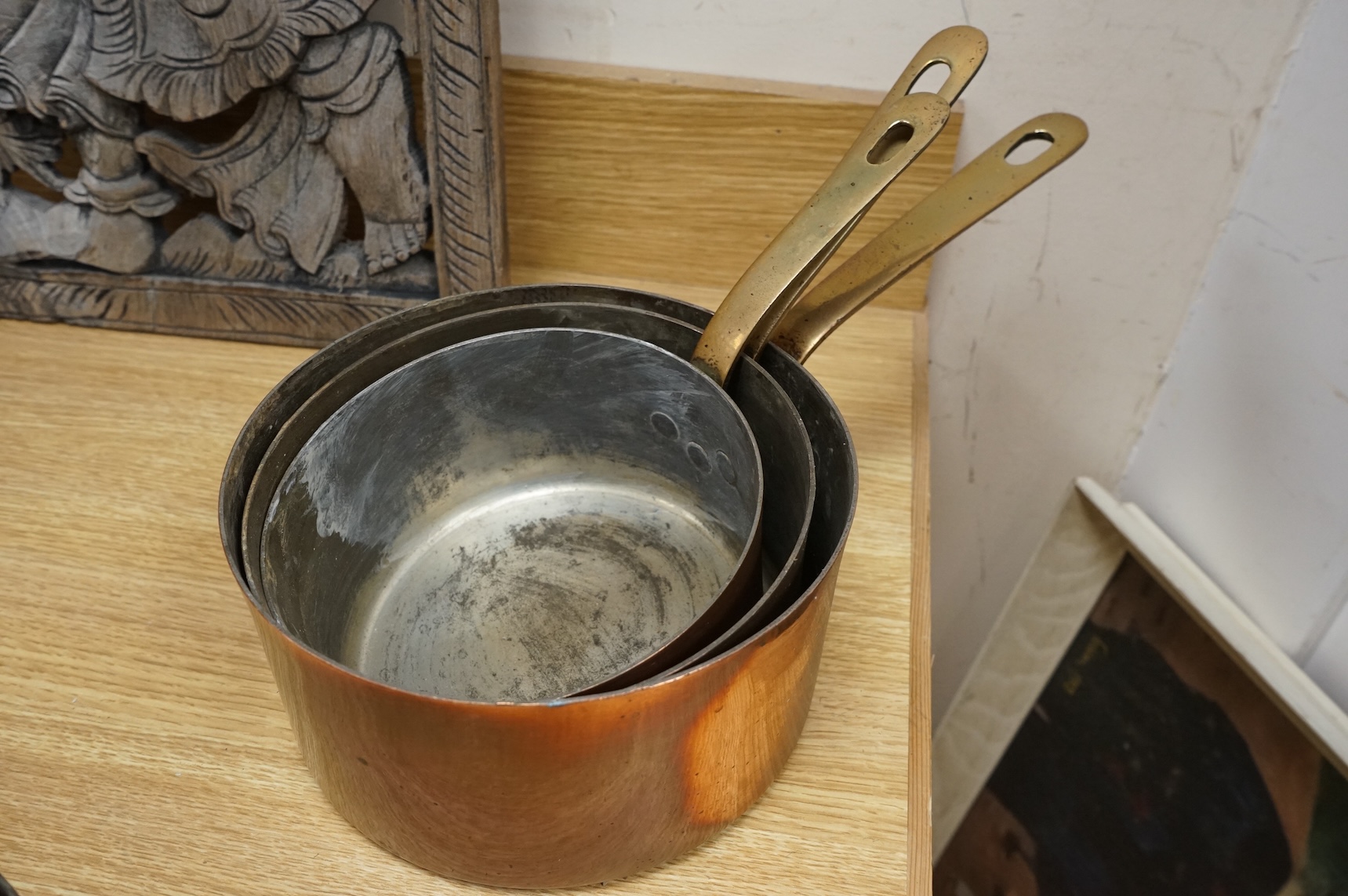 A set of three graduated copper and brass handled Saucepans and a similar set with pouring lid, largest 40cm in length